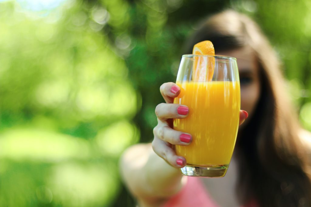 בחורה מחזיקה כוס מיץ תפוזים